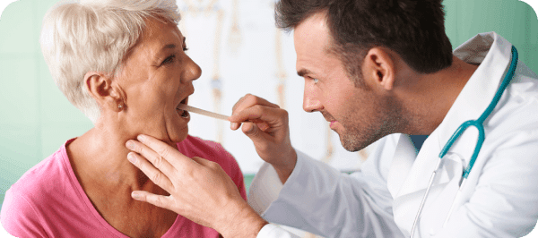 A mature lady's throat is being check by one of the best ENT doctor.