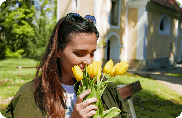 A beautiful woman being able to smell flowers after a surgery.