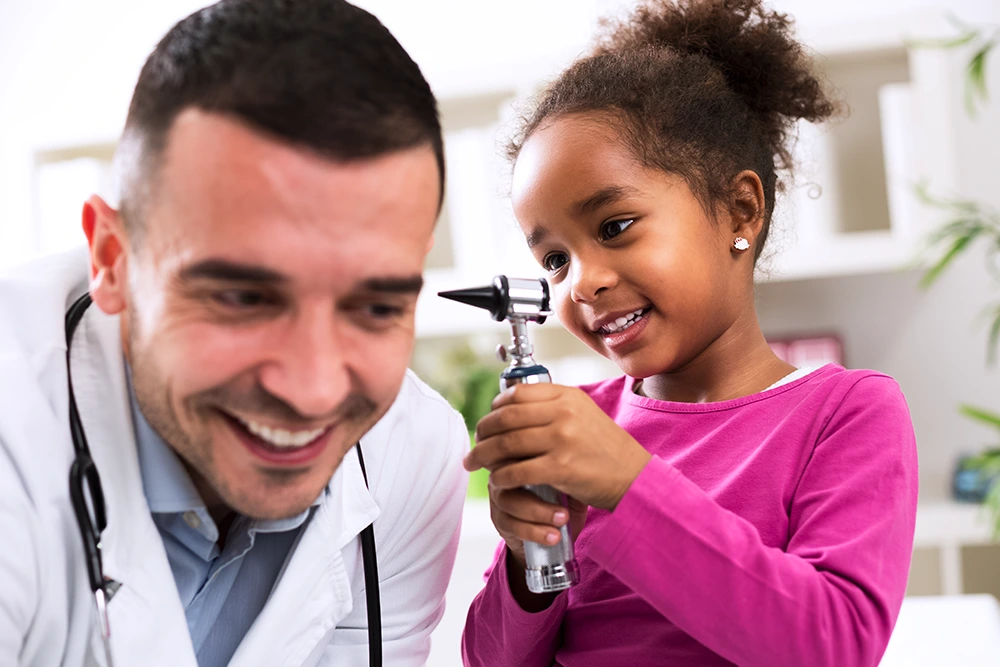 A young girl patient being taught how doctors check the ears.