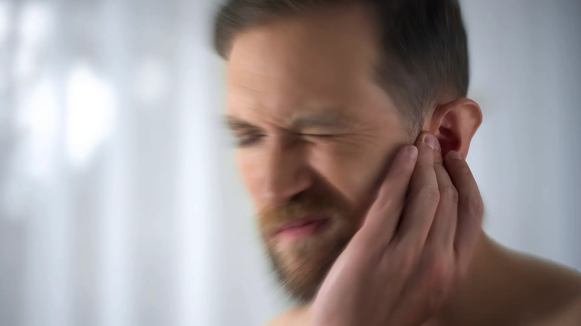 A guy showing he experiences pain around his ear.